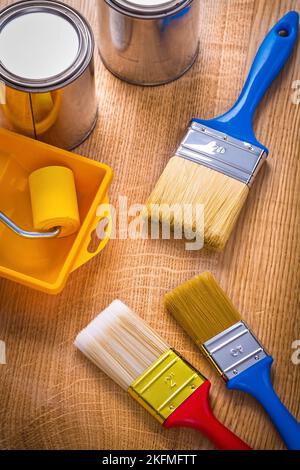 tray roller paint brushes cans on wooden board Stock Photo