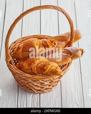 view baguettes and croissants in wicker basket on white boards Stock Photo
