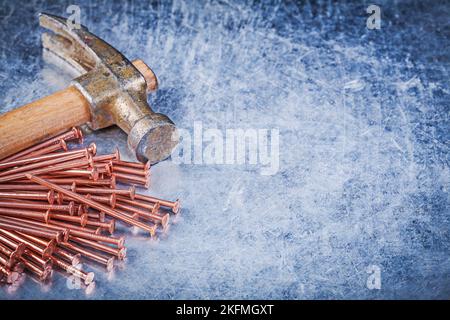 Vintage claw hammer brass construction nails on metallic background. Stock Photo