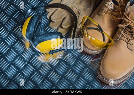 working boots yellow earphones and goggles on metalic sheet Stock Photo