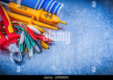 Yellow electrical tester crocodile clip cables blue construction plans nippers on metallic background electricity concept. Stock Photo