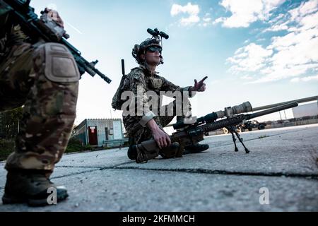 U.S. Army Green Berets from 10th Special Forces Group (Airborne) hold their position during training mission rehearsals with United Kingdom Royal Marines from 45 Commando at Grafenwöhr Training Area, Germany, Sept. 22, 2022. This Special Forces-led exercise is designed to improve their ability to work with the United Kingdom’s commando forces in a time of crisis. Stock Photo