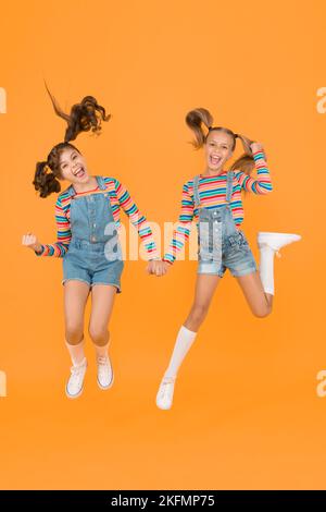 Best friends. Trendy and fancy. Emotional kids. Fashion shop. Modern  fashion. Kids fashion. Little girls wearing rainbow clothes. Happiness.  Girls long hair. Cute children same outfits communicating Stock Photo