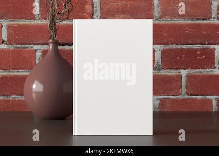 Vertical book cover mock up standing on a dark wooden desk with red brick wall background Stock Photo