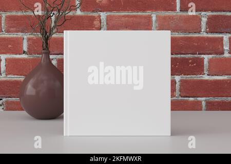 Square book cover mock up standing on a white desk with red brick wall background Stock Photo