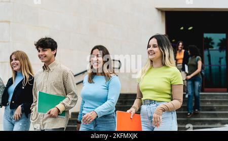 Young diverse students leaving university after lesson - Youth and education concept Stock Photo