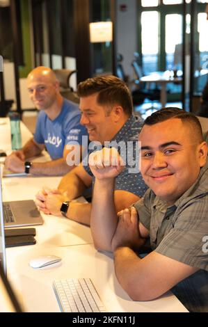 Tech. Sgt. Alex Tamayo (from right), a 162nd Wing security manager, works with Senior Master Sgt. Charles Givens, ARCWERX Public Affairs Specialist, and Capt Brett Mather, Corsair Ranch deputy chief of software, on a problem set during the recent ‘Hack the Ranch’ event in Tucson, Ariz. 162nd wing,INNOVATION,afwerx,arcwerx,corsair ranch,national guard, Stock Photo
