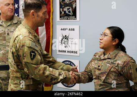 U.S. Army Spc. Jennifer M. Sanchez, Property Book NCO, 92Y, for Headquarters and Headquarters Company, 36th Combat Aviation Brigade, 'Task Force Mustang,' 36th Infantry Division (right), receives congratulations from Col. Scott P. Nicholas, commander of Task Force Mustang, while receiving her Certificate of Appreciation as the brigade's 'Hero of the Week' during a command and staff meeting held at Task Force Mustang headquarters, Camp Buehring, Kuwait, Sept. 28, 2022. Sanchez, a native of Nacogdoches, Texas, was recognized for her stellar performance and administrative excellence in overseeing Stock Photo