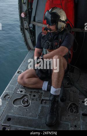 220928-N-LI114-1142 WATERS EAST OF THE KOREAN PENINSULA (Sept. 28, 2022) Naval Air Crewman (Helicopter) 2nd Class Tyler Williamson, from Inola, Oklahoma, looks out of an MH-60S Seahawk helicopter, attached to the Golden Falcons of Helicopter Sea Combat Squadron (HSC) 12, deployed aboard the U.S. Navy’s only forward-deployed aircraft carrier, USS Ronald Reagan (CVN 76), in waters east of the Korean peninsula, Sept. 28. HSC 12, originally established as Helicopter Anti-Submarine Squadron (HS) 2 on March 7, 1952, is the oldest active operational Navy helicopter squadron. The Ronald Reagan Carrier Stock Photo