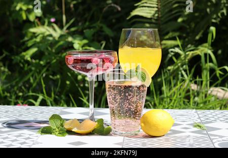 Refreshing summer cocktails on a garden table. Close up photo of glasses with various drinks. Party in a garden. Stock Photo