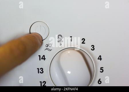 Man's hand presses the start button on the washing machine Stock Photo