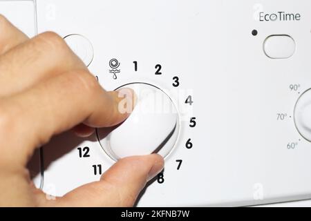 Man's hand presses the buttons on the control panel of the washing machine Stock Photo
