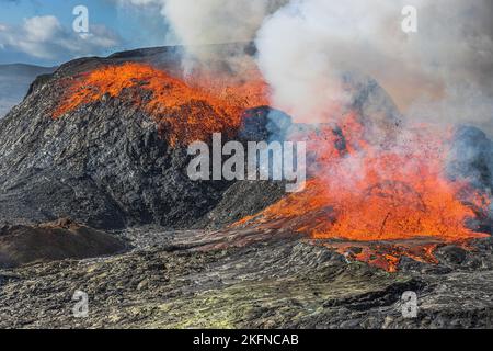 active volcano on Iceland. Eruption with lava flow from a volcanic crater on the Reykjanes peninsula. Glowing hot lava with a small fountain. Stock Photo