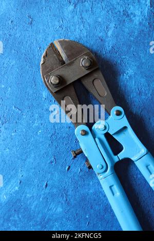 Tools on blue textured background with copy space. Vintage pliers close up photo. Handyman tools top view photo. Stock Photo