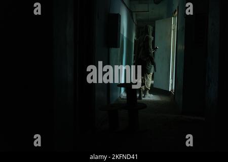 a man walking in a dark corridor of abandoned build, with flashlight in darkness Stock Photo
