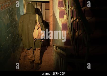 Man with backpack in an abandoned building entrance exit. Post apocalypse. Man traveling on foot in a post-apocalyptic world in search of water and fo Stock Photo