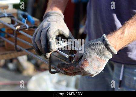 Close up photo of man holding pliers. Man works with reinforcement steel. Construction work in details. Stock Photo