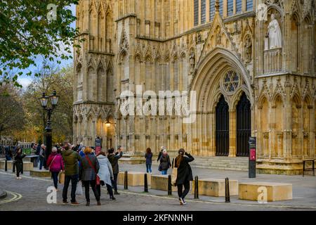 People taking photos of new Elizabeth 2 statue on niche wearing Garter Robes (orb, sceptre) - York Minster west front, North Yorkshire, England, UK. Stock Photo