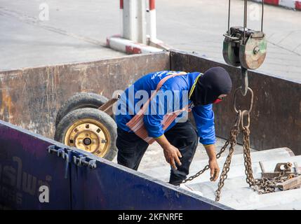 SAMUT PRAKAN, THAILAND, SEP 16 2022, A worker attaches chains from a crane to concrete tubes on the load space of a truck Stock Photo