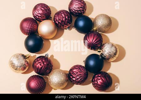 Circle frame of colorful Christmas balls on light beige background with sharp shadows. Top view, flat lay, copy space. Stock Photo