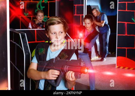 Excited boy aiming laser gun at other players during laser tag g Stock Photo