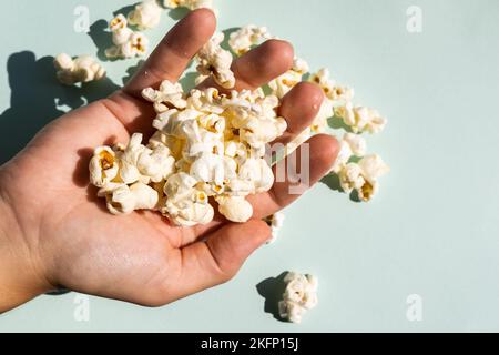 Hand with tasty salt popcorn. Stock Photo