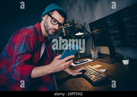 Photo of smart ponder guy dressed eyewear watching working apple samsung modern device indoors workstation workshop home Stock Photo