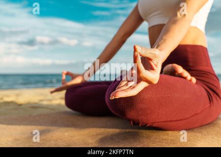 Woman meditating on the beach at sunset - closeup on the hands - crop shot - unrecognizable person - mindfulness, mental health and people lifestyle c Stock Photo