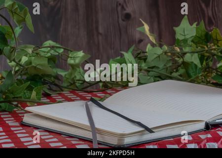 A closeup shot of an open daily journal on a picnic table with ivy leaves Stock Photo