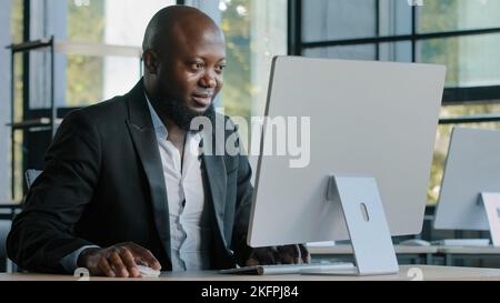 African american businessman commercial agent expert site in modern office work on computer develop website coding program search data online Stock Photo