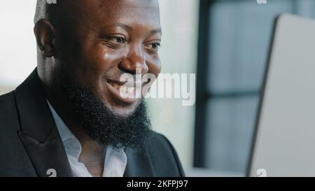 Smiling african businessman adult professional employee web designer chatting in networks using wifi internet at office searching digital information Stock Photo