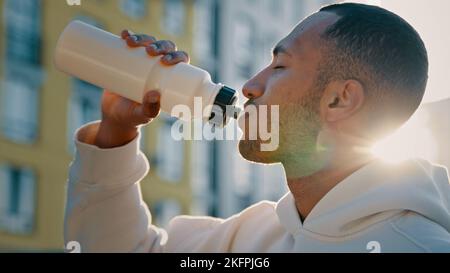 Athlete sportsman latina handsome man african american guy runner bodybuilder drink cold fresh water healthy beverage protein cocktail after sport Stock Photo