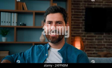 Close up portrait of handsome brunet caucasian man adult happy successful homeowner sit in living room house interior looking at camera smiling male Stock Photo