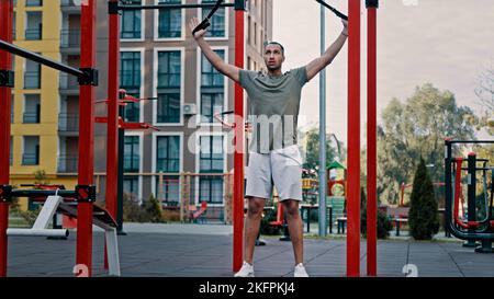 Powerful athlete african latina man sportsman strong guy doing legs exercise using weight TRX straps training masculine force athletic male squat on Stock Photo