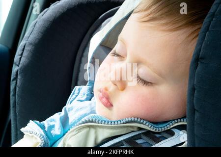 cute little boy sleeping in car seat close view portrait, soft day light Stock Photo