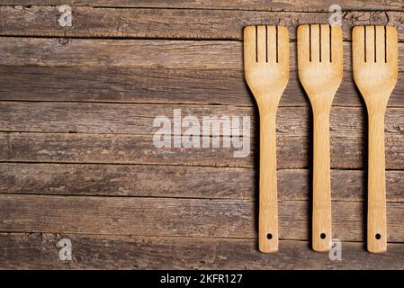 Background of rustic and aged wooden slats with three wooden forks on one side. Stock Photo