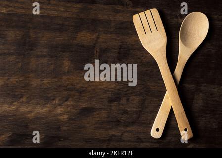 Crossed wooden spoon and fork on an old rustic wooden background. Stock Photo