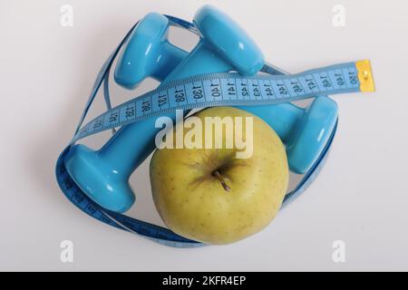 Dumbbells in bright green color, measure tape and fruit Stock Photo