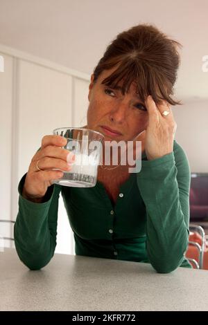 mature woman with headache taking soluble painkillers Stock Photo