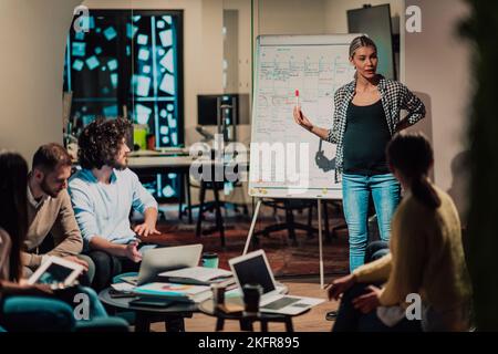 A pregnant businesswoman leads a creative meeting of a diverse business team in a modern coworking Stock Photo