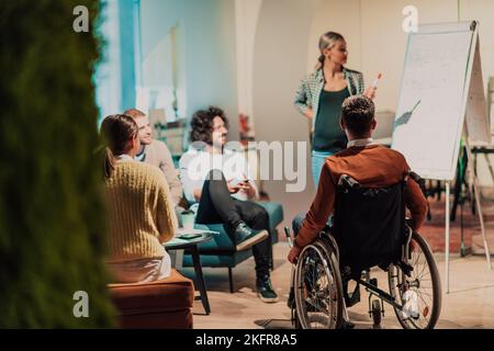 A pregnant businesswoman leads a creative meeting of a diverse business team in a modern coworking Stock Photo
