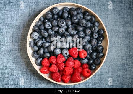 Fresh selected raspberries and blueberries in a bowl. Healthy snack. Berries for dessert. Close-up. Stock Photo