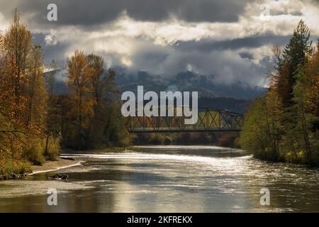 Moody fall day along the Snoqualmie River under threating clouds and with glistening waer Stock Photo