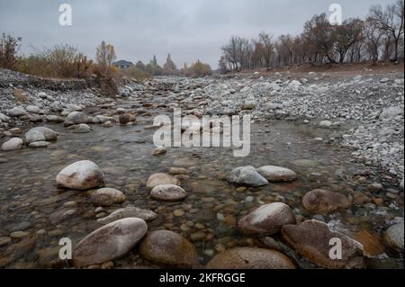 Slow and not deep mountain river with rounded stones Stock Photo