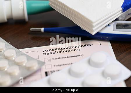 Stuttgart, Germany. 18th Nov, 2022. A fever thermometer, medication and a doctor's certificate of incapacity for work (sick note) are lying on a bedside table (posed scene). With the cold season, influenza infections are on the rise again. Credit: Bernd Weißbrod/dpa/Alamy Live News Stock Photo