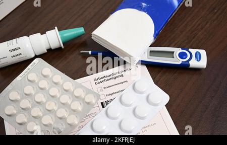 Stuttgart, Germany. 18th Nov, 2022. A fever thermometer, medication and a doctor's certificate of incapacity for work (sick note) are lying on a bedside table (posed scene). With the cold season, influenza infections are on the rise again. Credit: Bernd Weißbrod/dpa/Alamy Live News Stock Photo