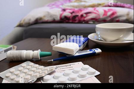 Stuttgart, Germany. 18th Nov, 2022. A fever thermometer, medication and a doctor's certificate of incapacity for work (sick note) are lying on a bedside table (posed scene). With the cold season, influenza infections are on the rise again. Credit: Bernd Weißbrod/dpa/Alamy Live News Stock Photo