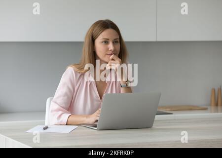 Pensive freelancer woman working on laptop at home Stock Photo
