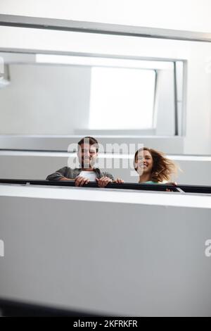 Feeling positive about our business. two people in stairwell smiling while looking down at you. Stock Photo