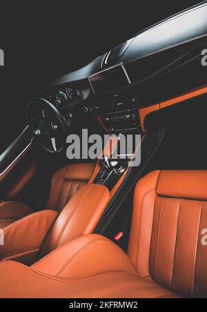 Orange red sand leather luxury car inside Interior - steering wheel, shift lever and dashboard. Stock Photo